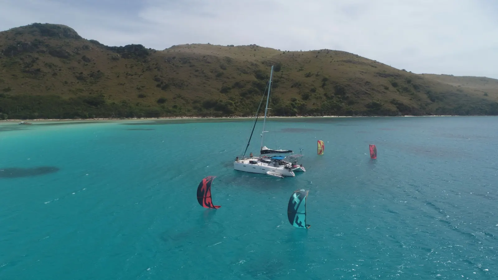 Soniya anchored near beach with multiple kites flying nearby