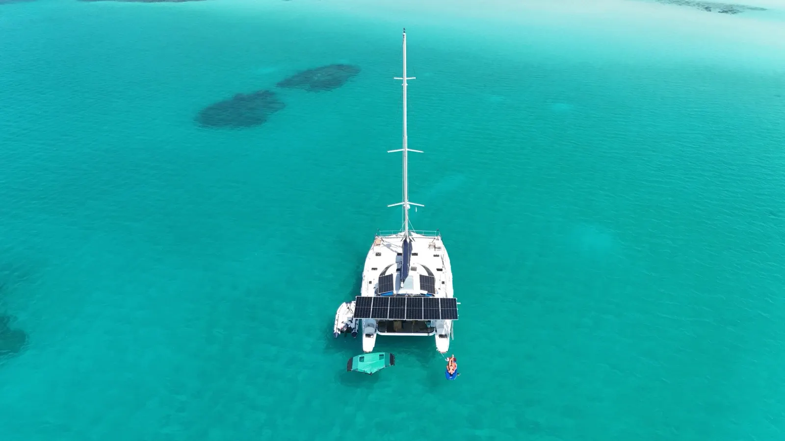 Aerial top-down of catamaran near shoreline with kite wing