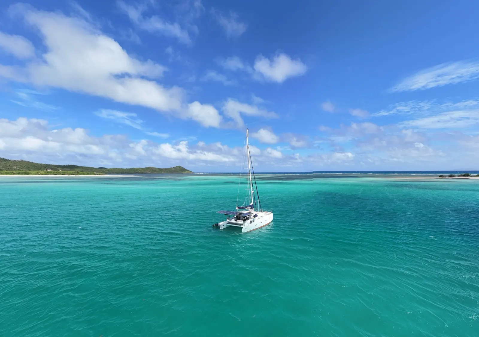 Panoramic aerial of Soniya anchored with kite wing nearby, islands beyond