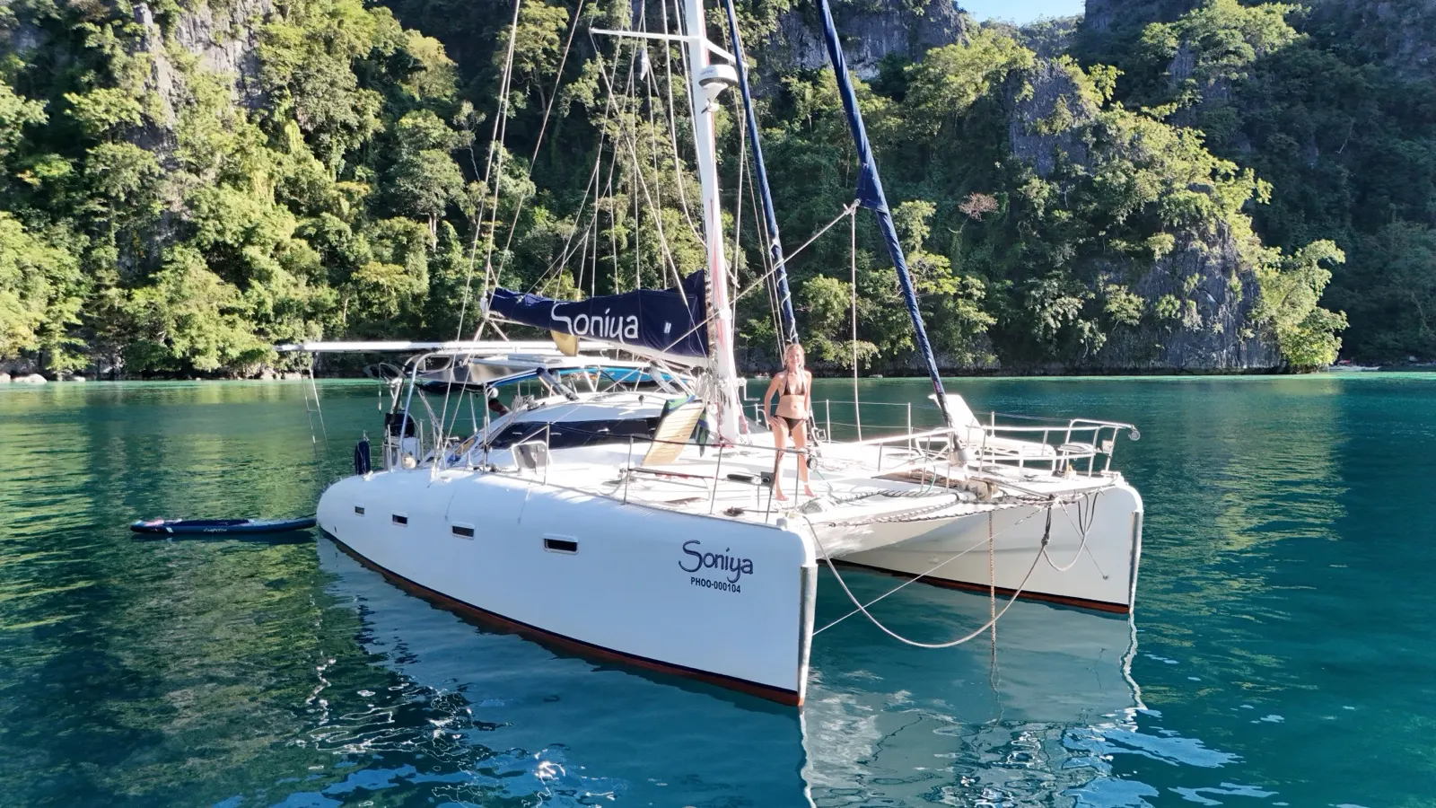 High-res aerial of Soniya anchored in a limestone cove, woman on bow