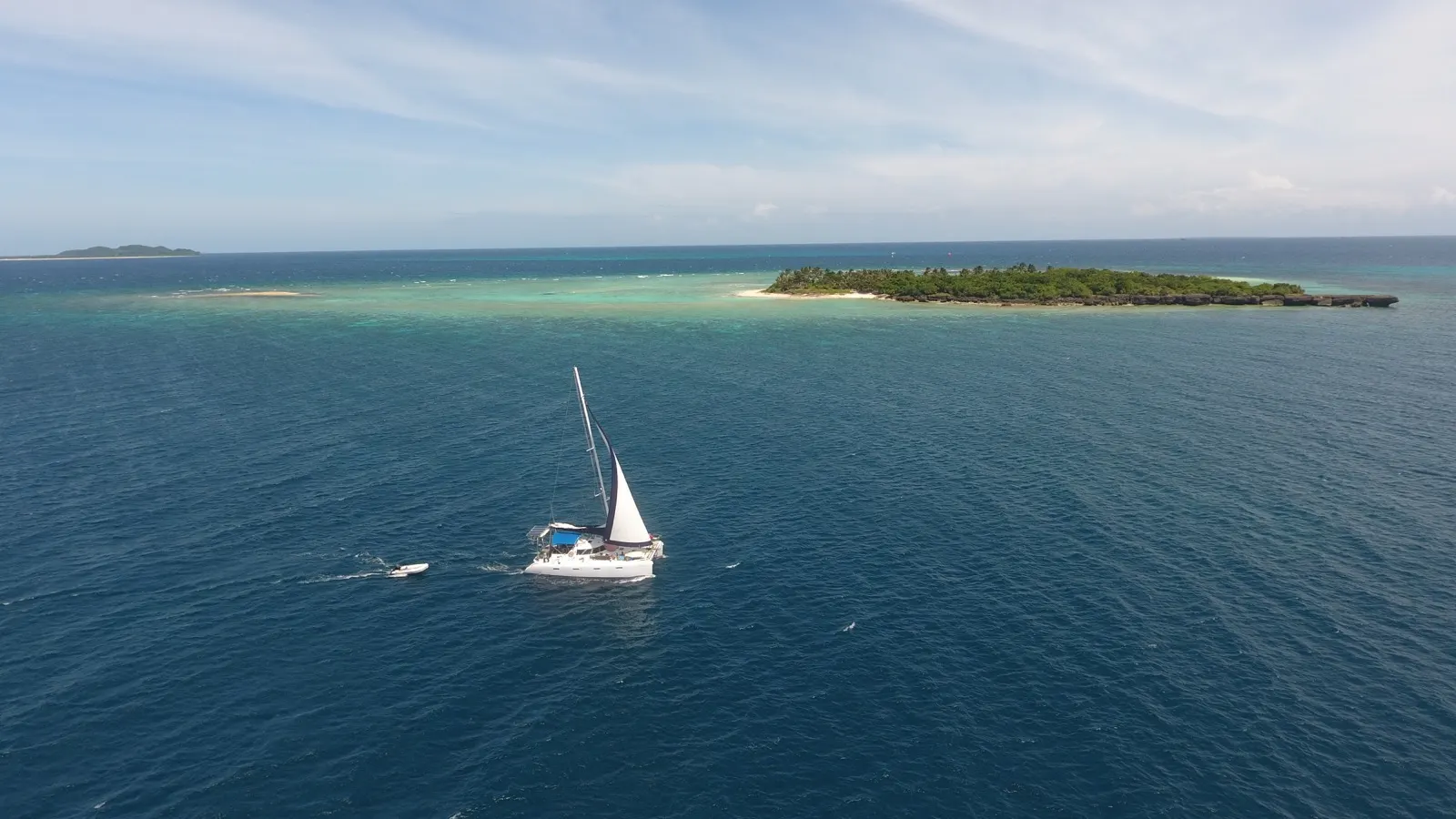 Soniya sailing near a small tree-covered island