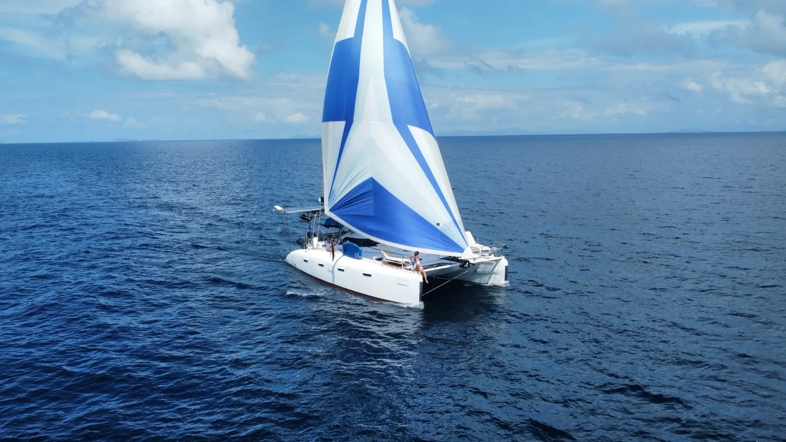 Soniya sailing under blue-and-white spinnaker