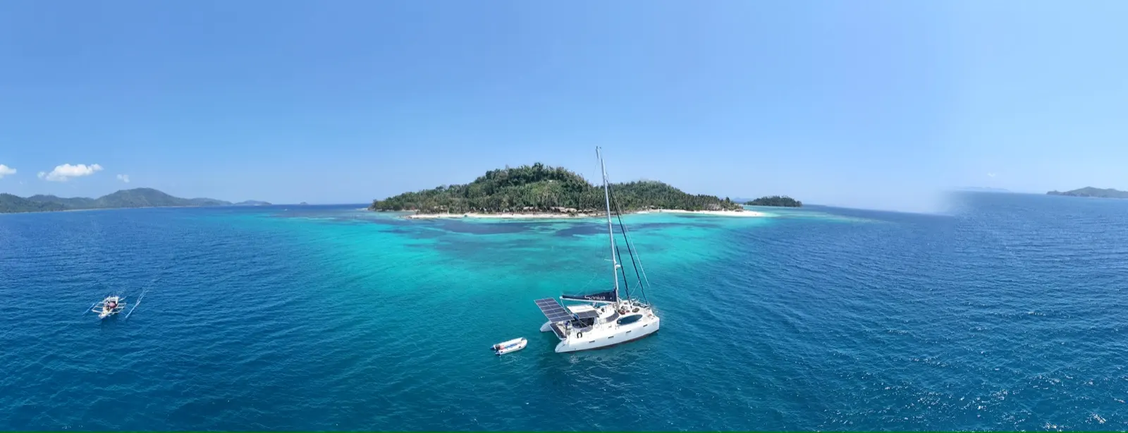 Wide panorama of Soniya anchored near island and reef