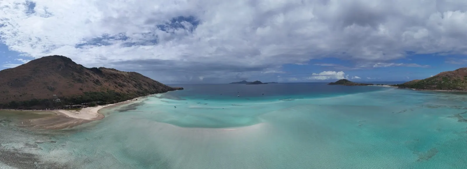 Panoramic bay view with sandbar and anchored boats