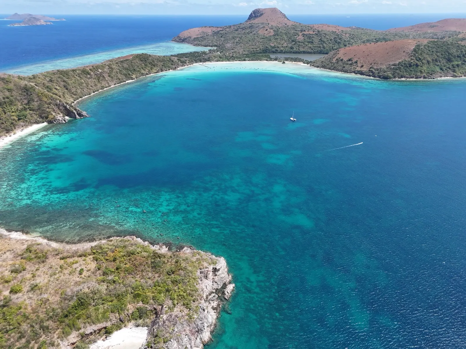 Aerial bay with mountain peak, catamaran anchored