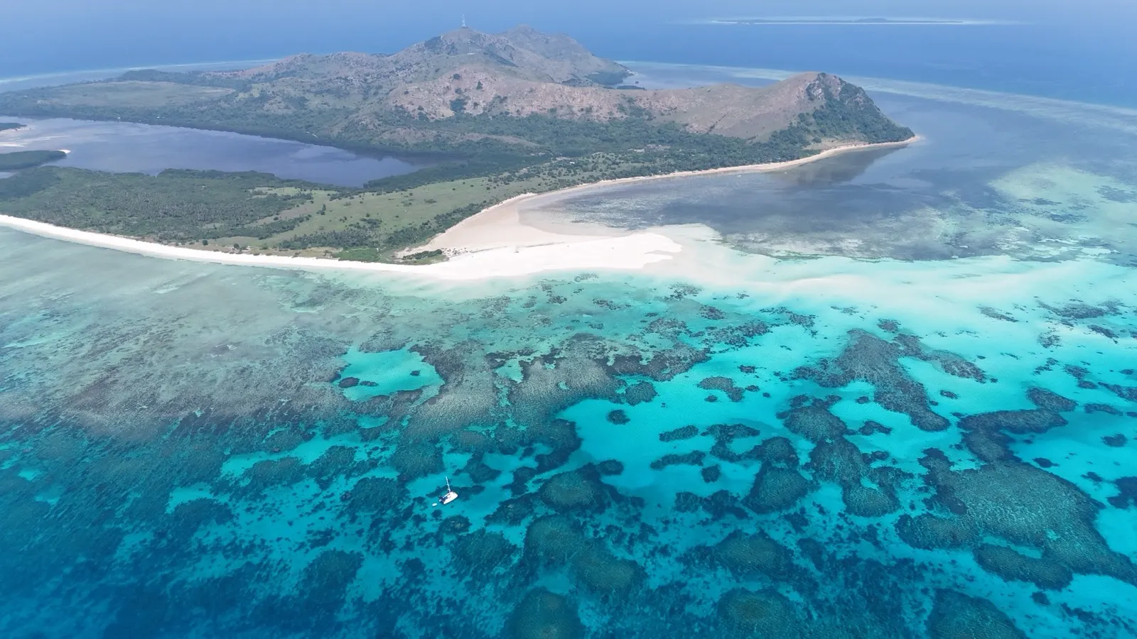 Wide aerial of island, sandbar, catamaran anchored