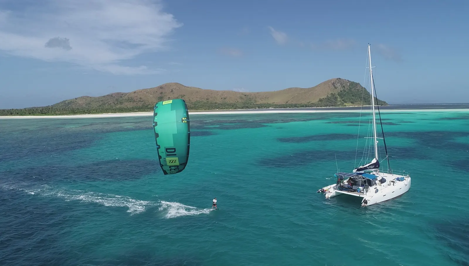 Soniya anchored with a kitesurfer riding nearby, green kite