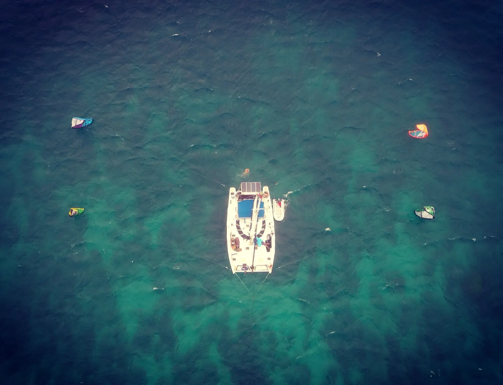 Aerial view of catamaran with four kites deployed around it