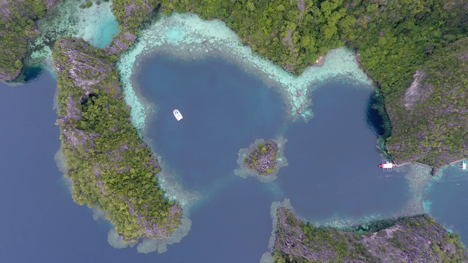Heart-shaped lagoon surrounded by limestone cliffs, small boat