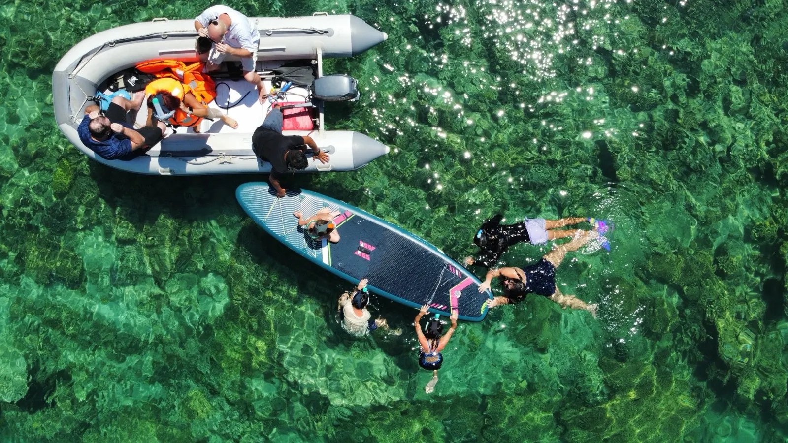 Guests jumping into the water off a paddleboard near reef
