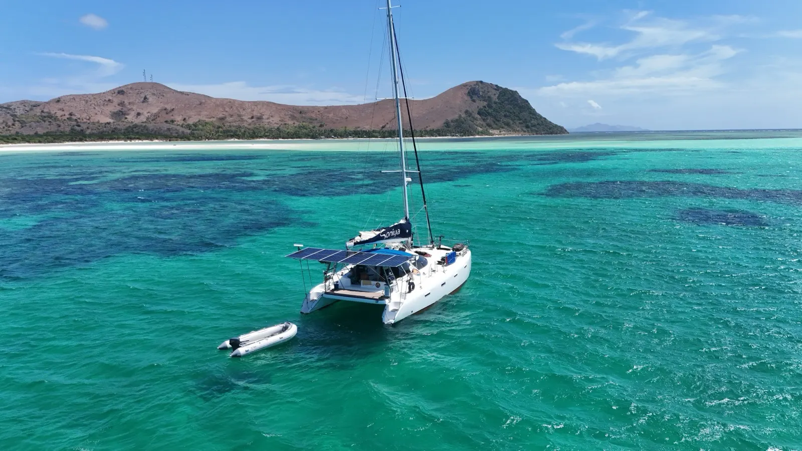 Catamaran anchored off beach, mountain backdrop