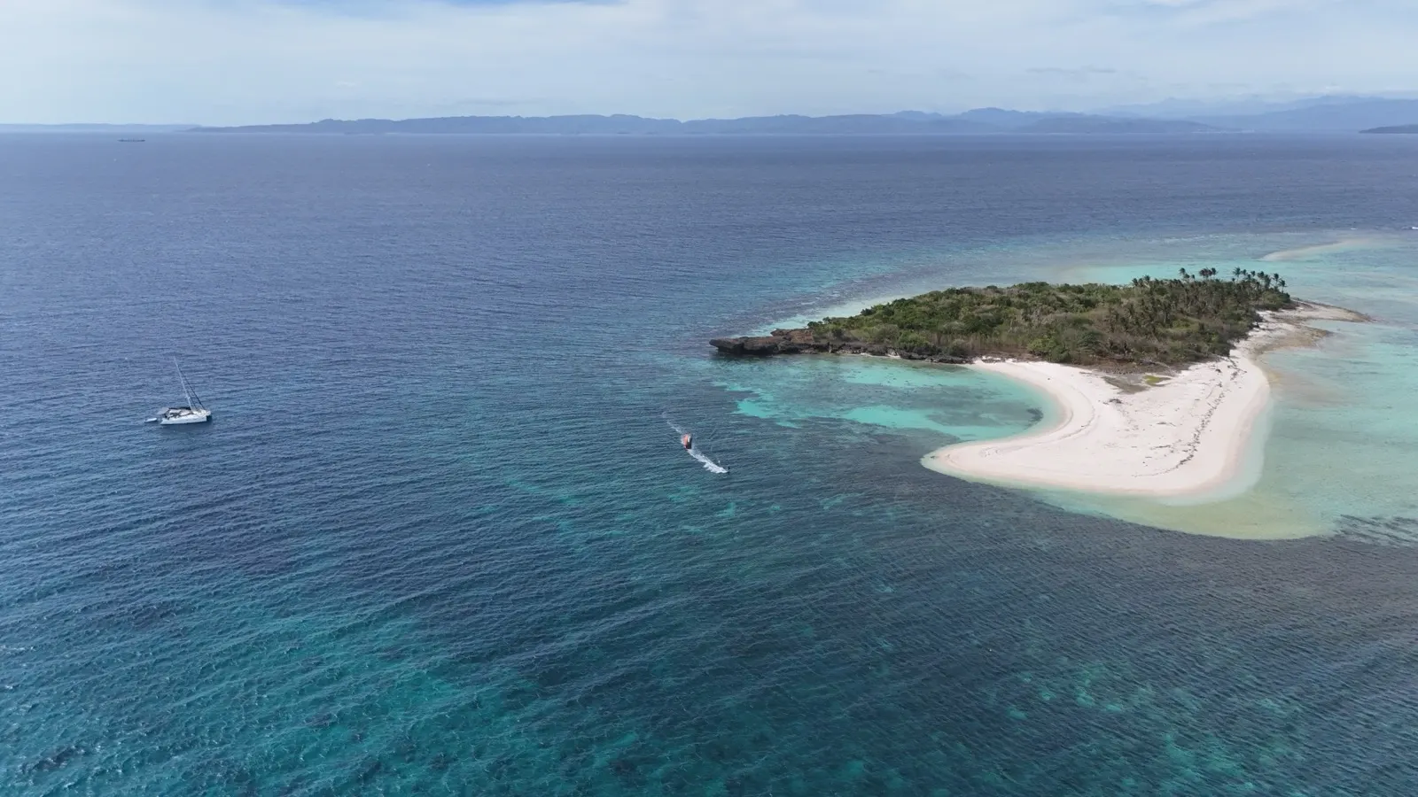 Wide aerial of catamaran, dinghy, and island