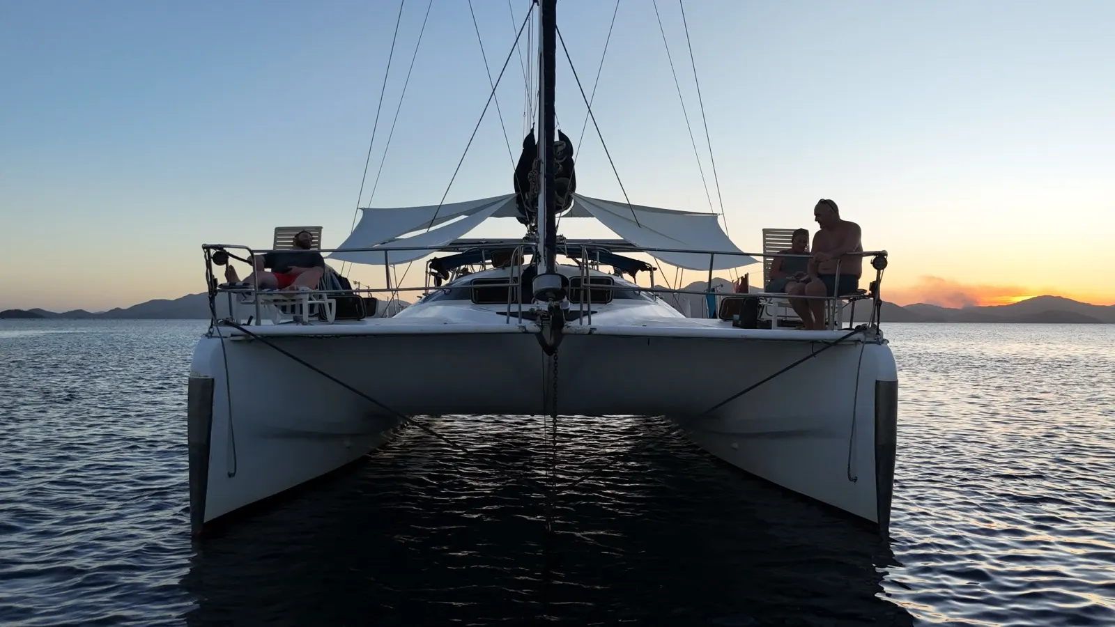 Catamaran stern with guest, mountains and reef beyond