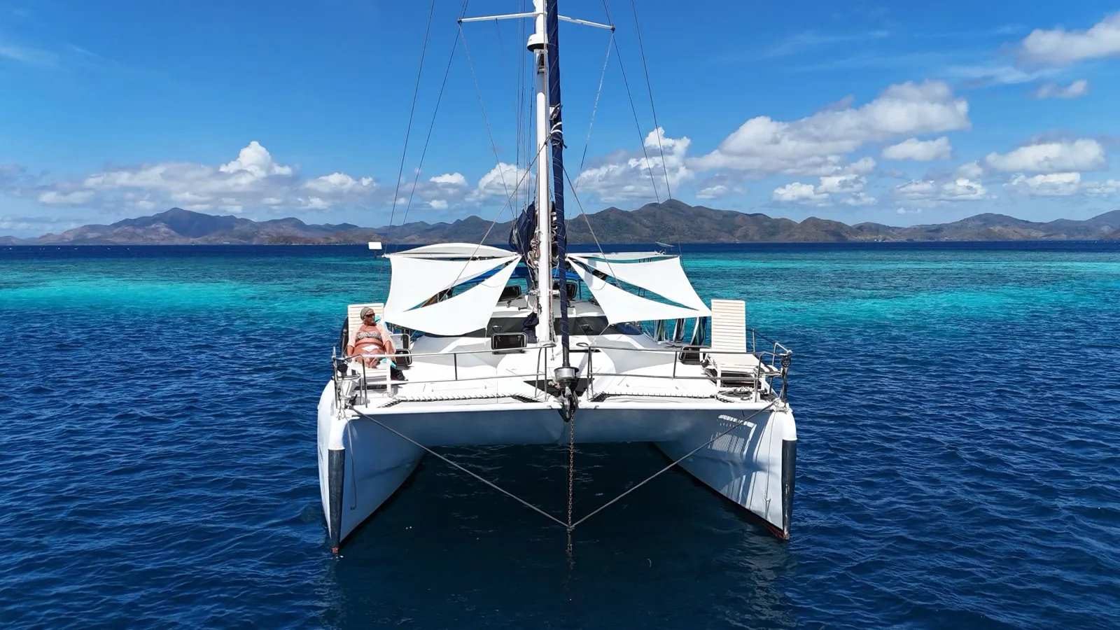 Catamaran side view under sail, solar panels visible