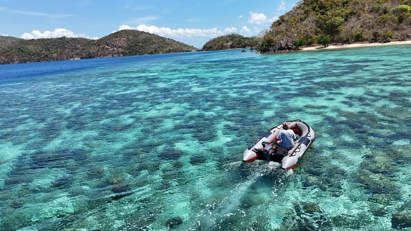 Catamaran under sail with island backdrop