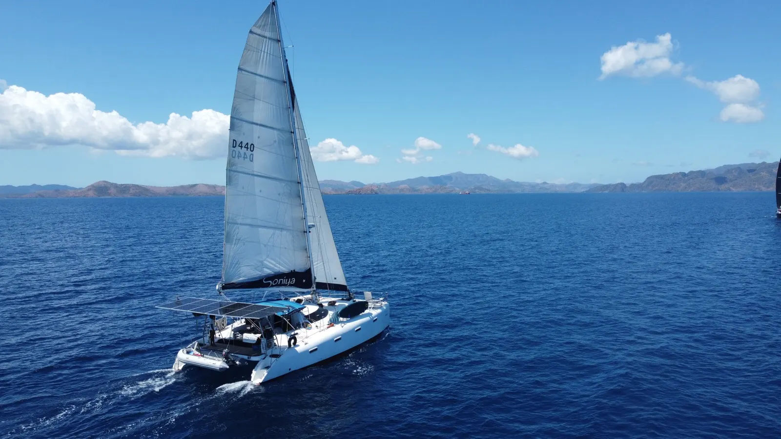 Catamaran under spinnaker, crew member visible on bow