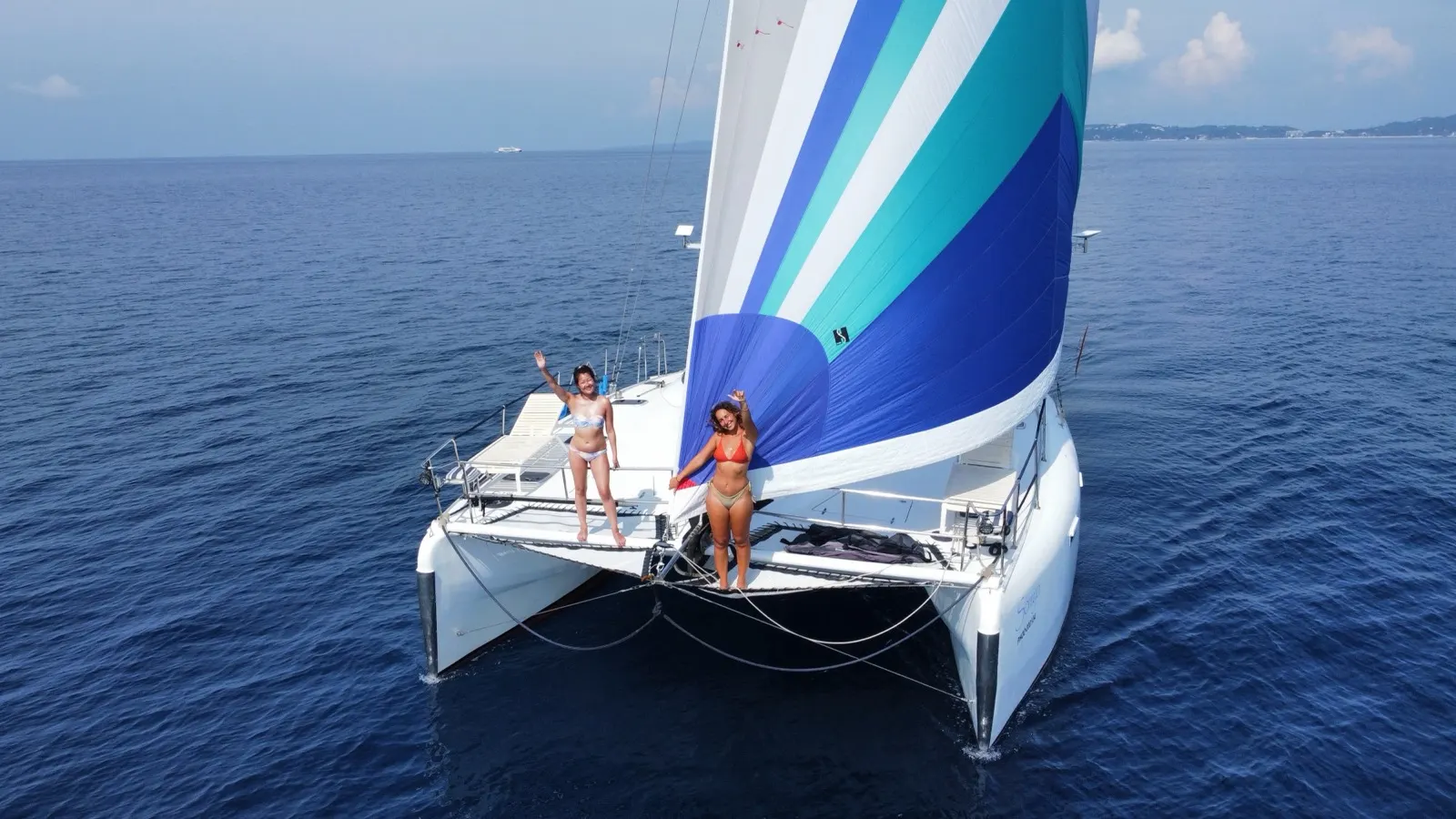 Woman standing at bow beside blue spinnaker