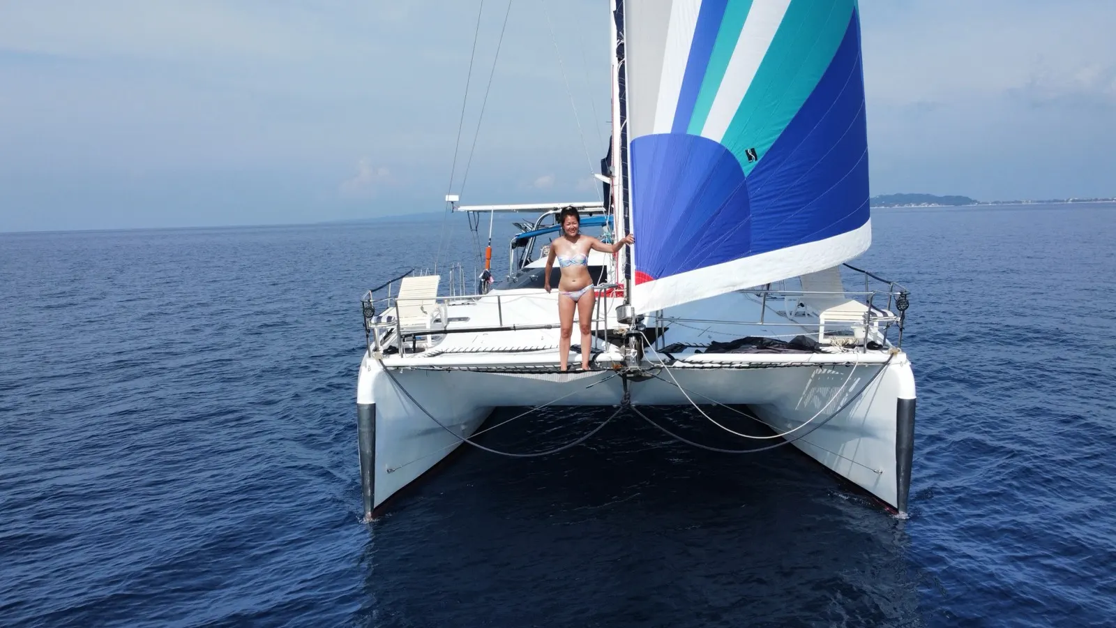 Woman at bow trampoline beside spinnaker