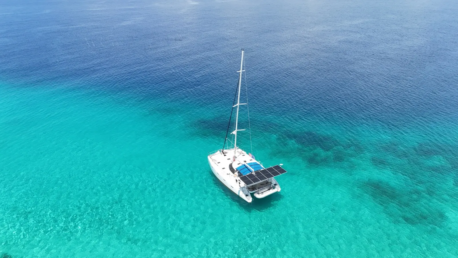 Catamaran alone, turquoise-to-blue water gradient
