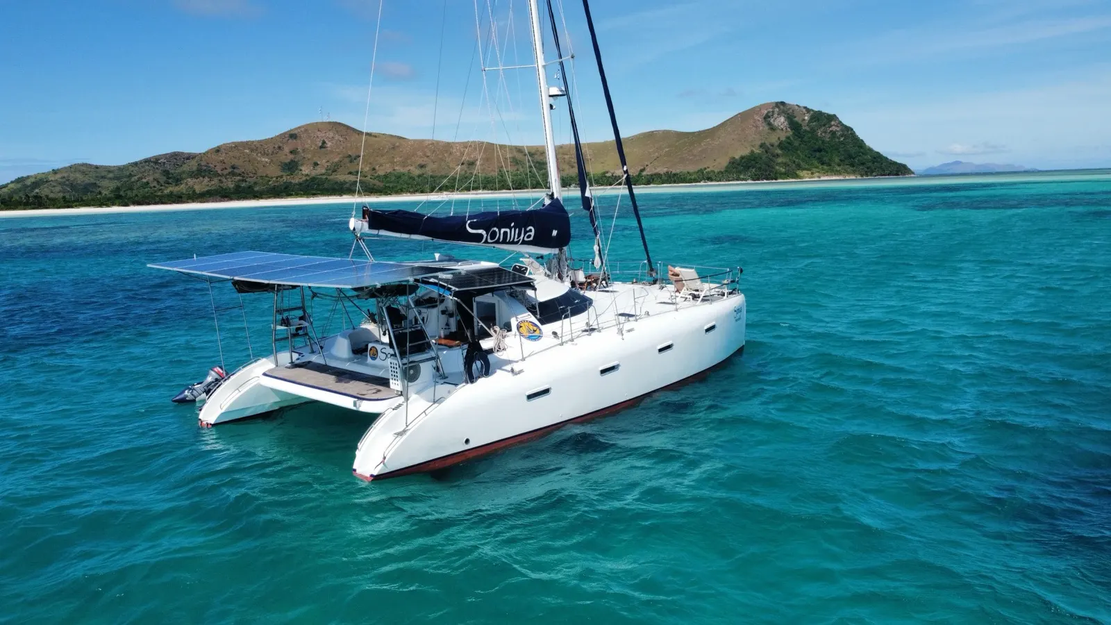 Soniya anchored in turquoise lagoon off a green island