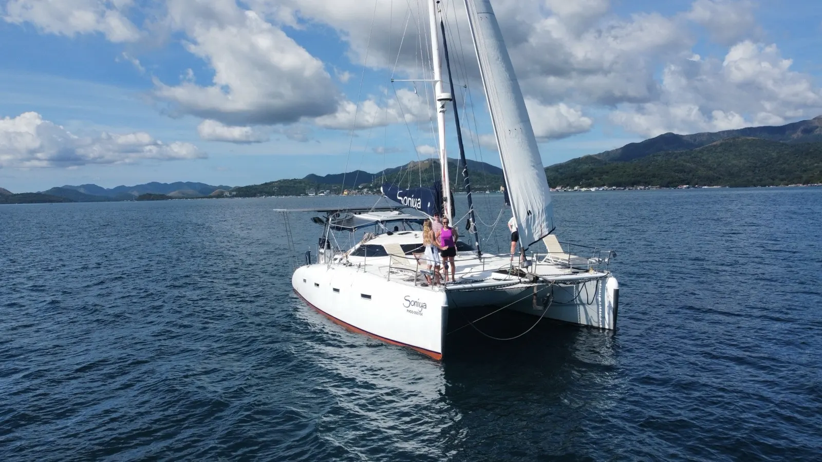 Soniya sailing with guests posing on deck near the bow
