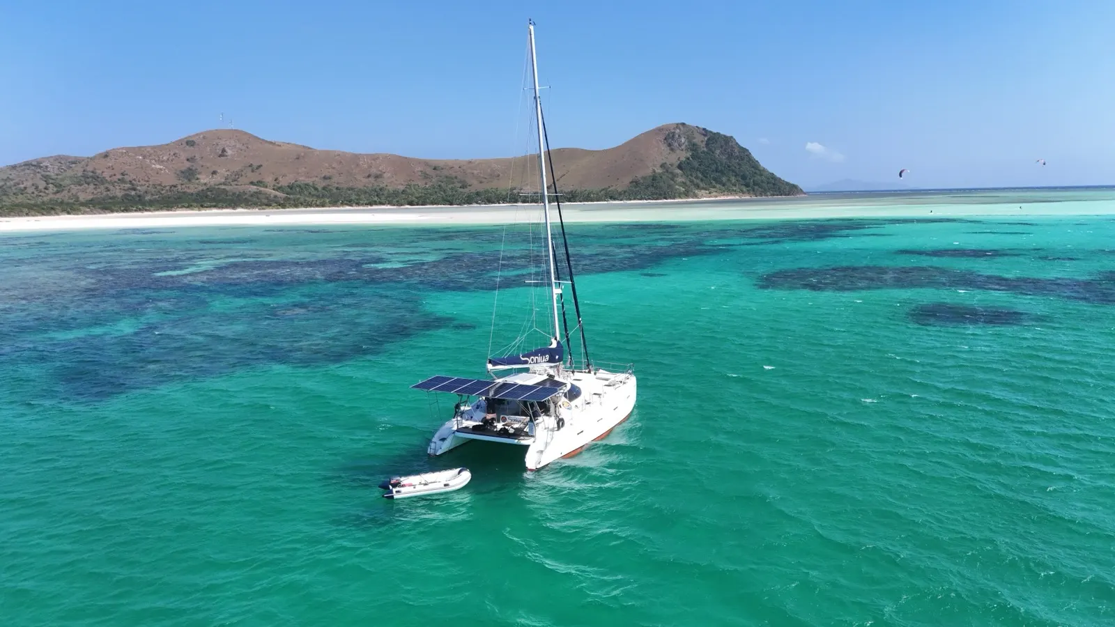 Soniya close to reef and beach, kite visible in distance