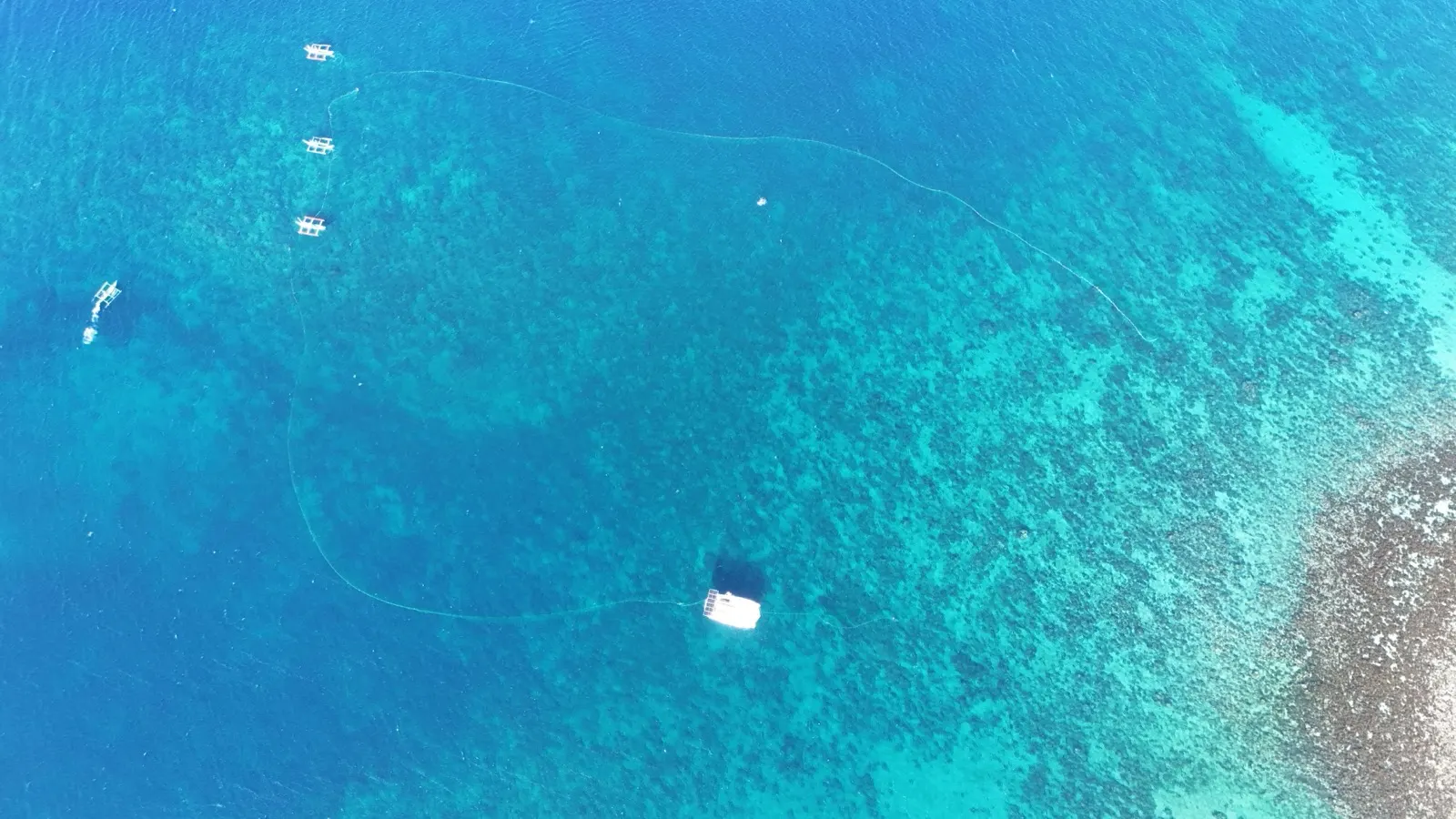 Aerial of fish cages and boats over a reef