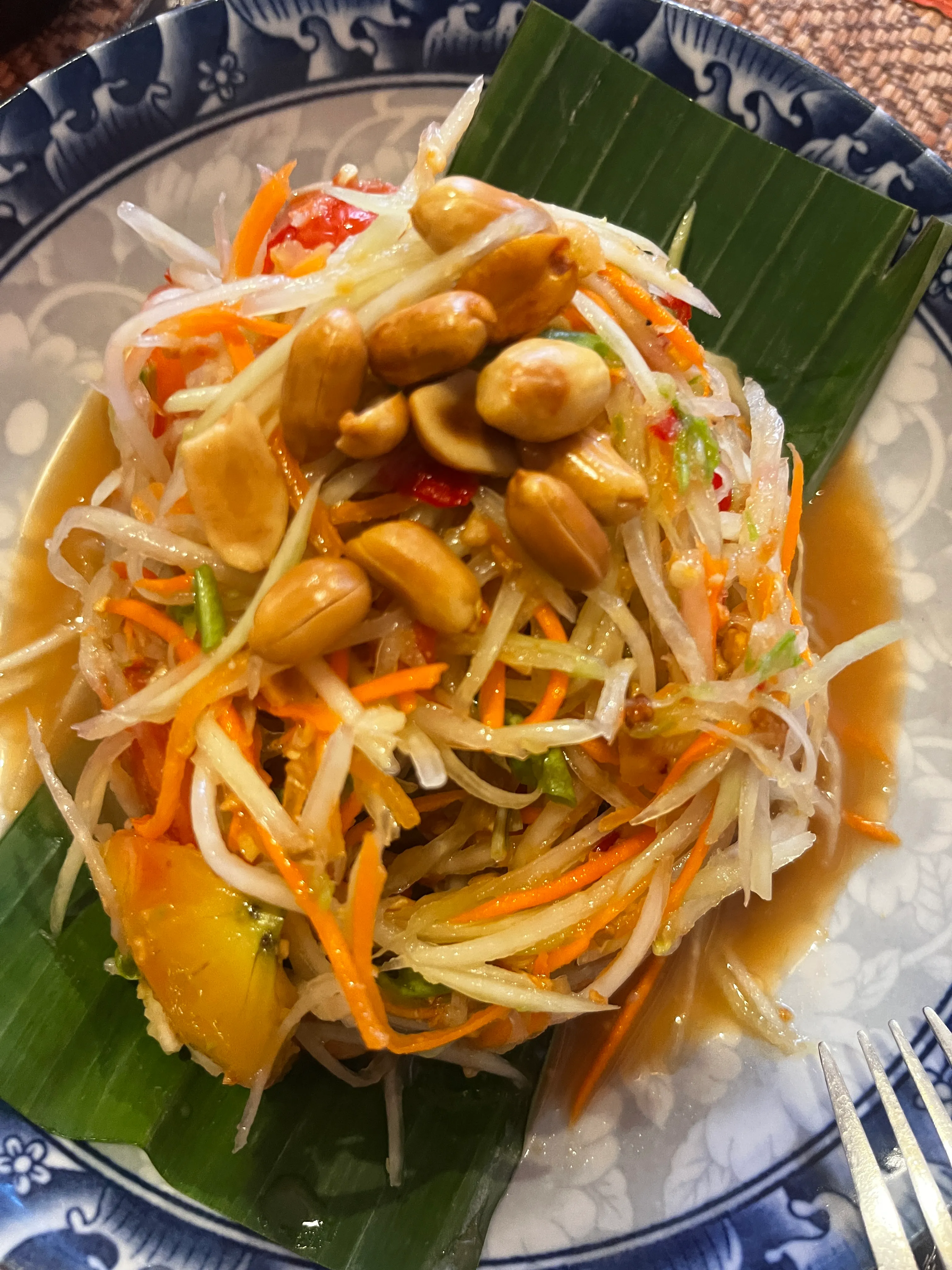 Green papaya salad with peanuts on a banana leaf