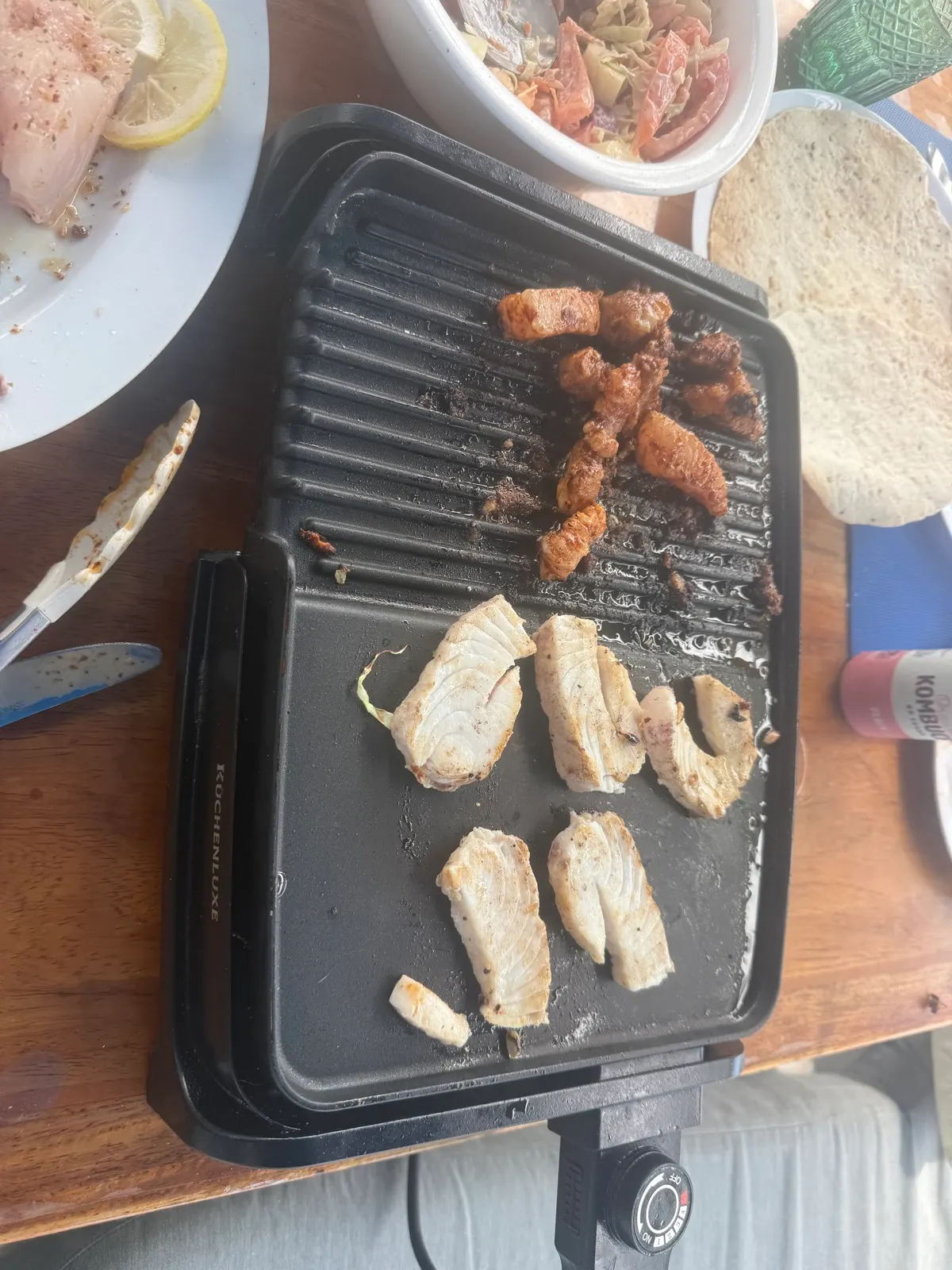 Grilled fish and meat cooking on tabletop grill