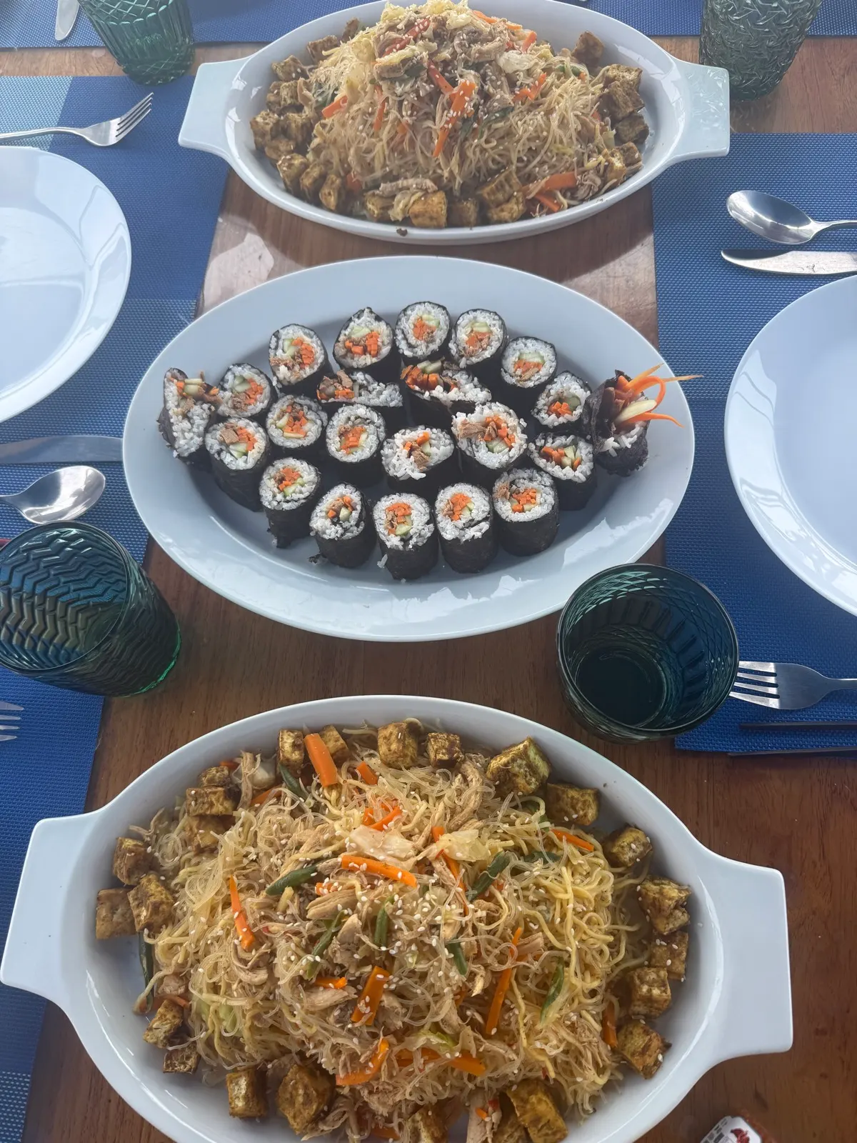 Noodles, sushi rolls and tofu dishes spread on table