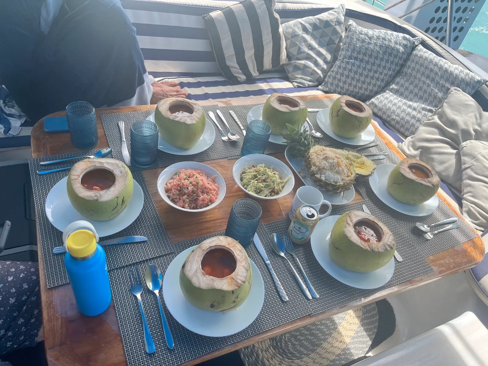 Full table of coconuts, salads, pineapple rice on deck