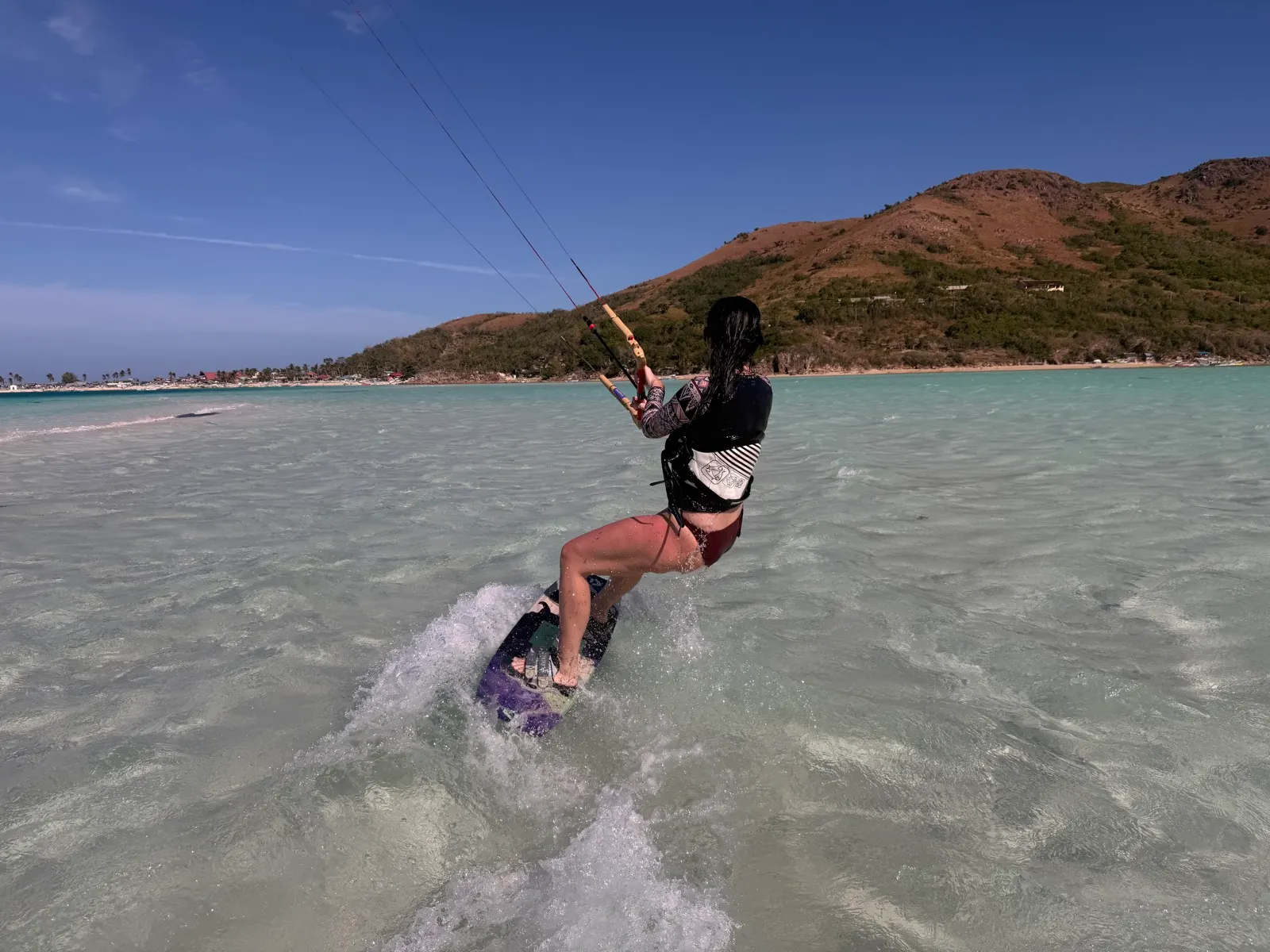 Woman kiteboarding through shallow turquoise water