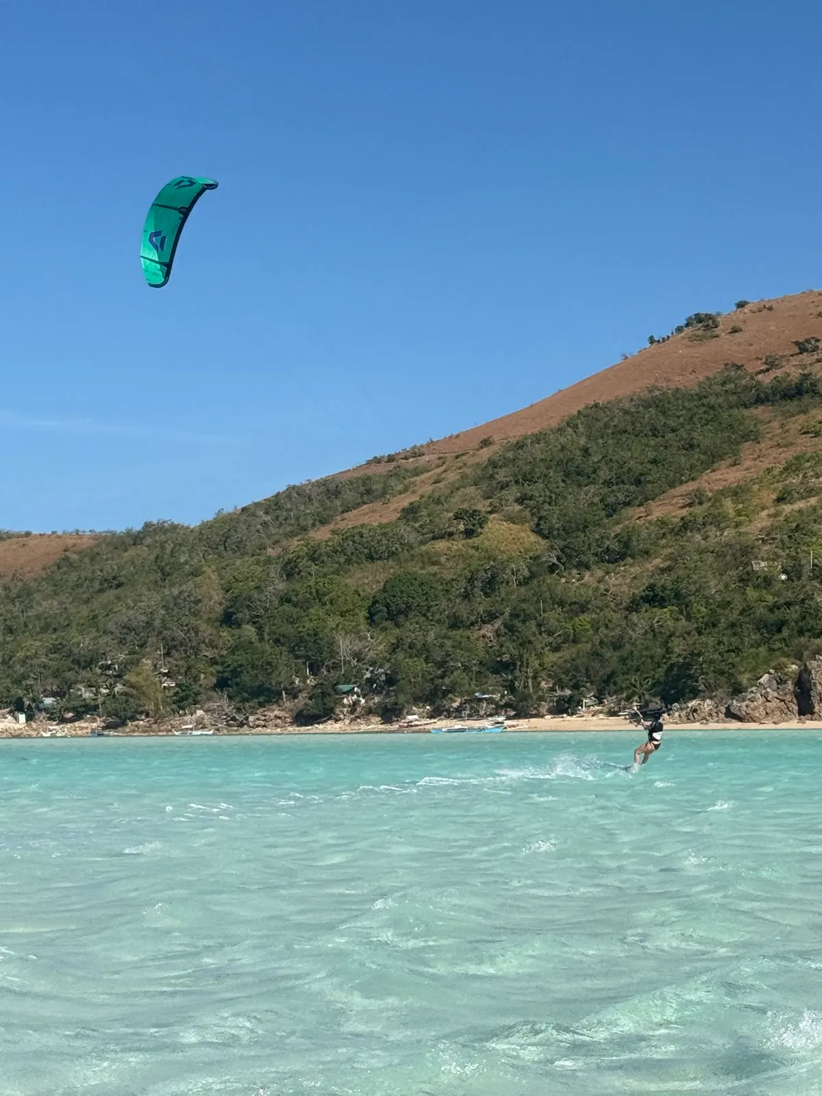 Aerial shot of kiter near shoreline, village visible
