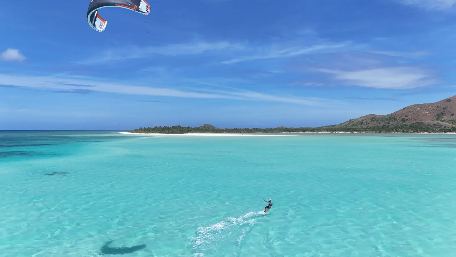 Kitesurfer with kite over shallow lagoon, island behind