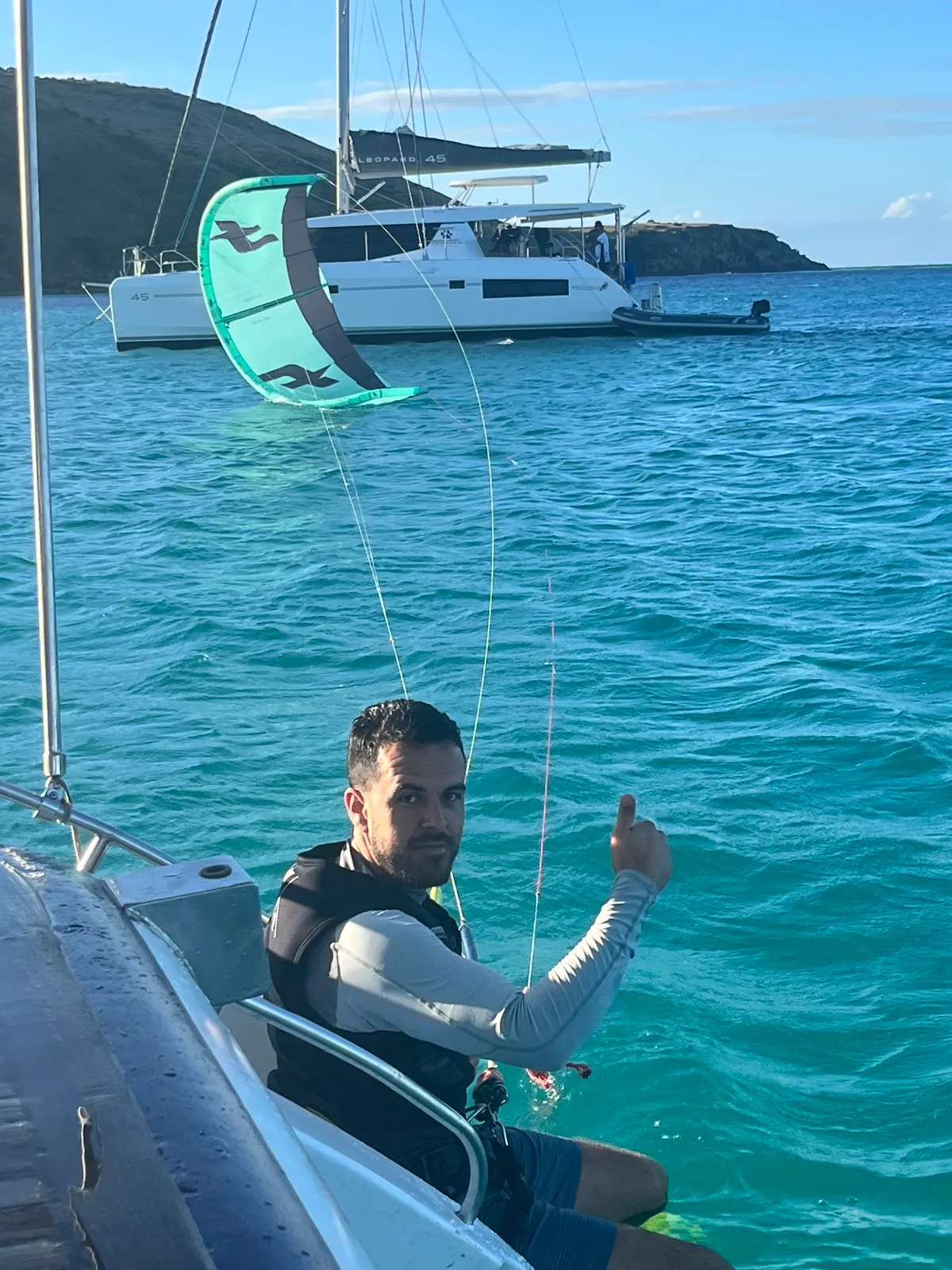 Man giving thumbs up holding kite bar on catamaran
