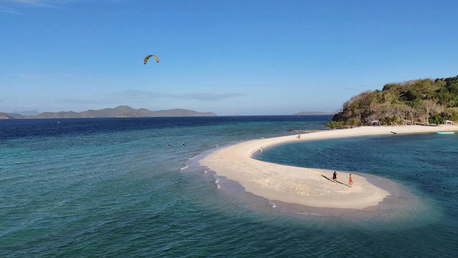 Kitesurfer's kite over a sandbar with beachgoers