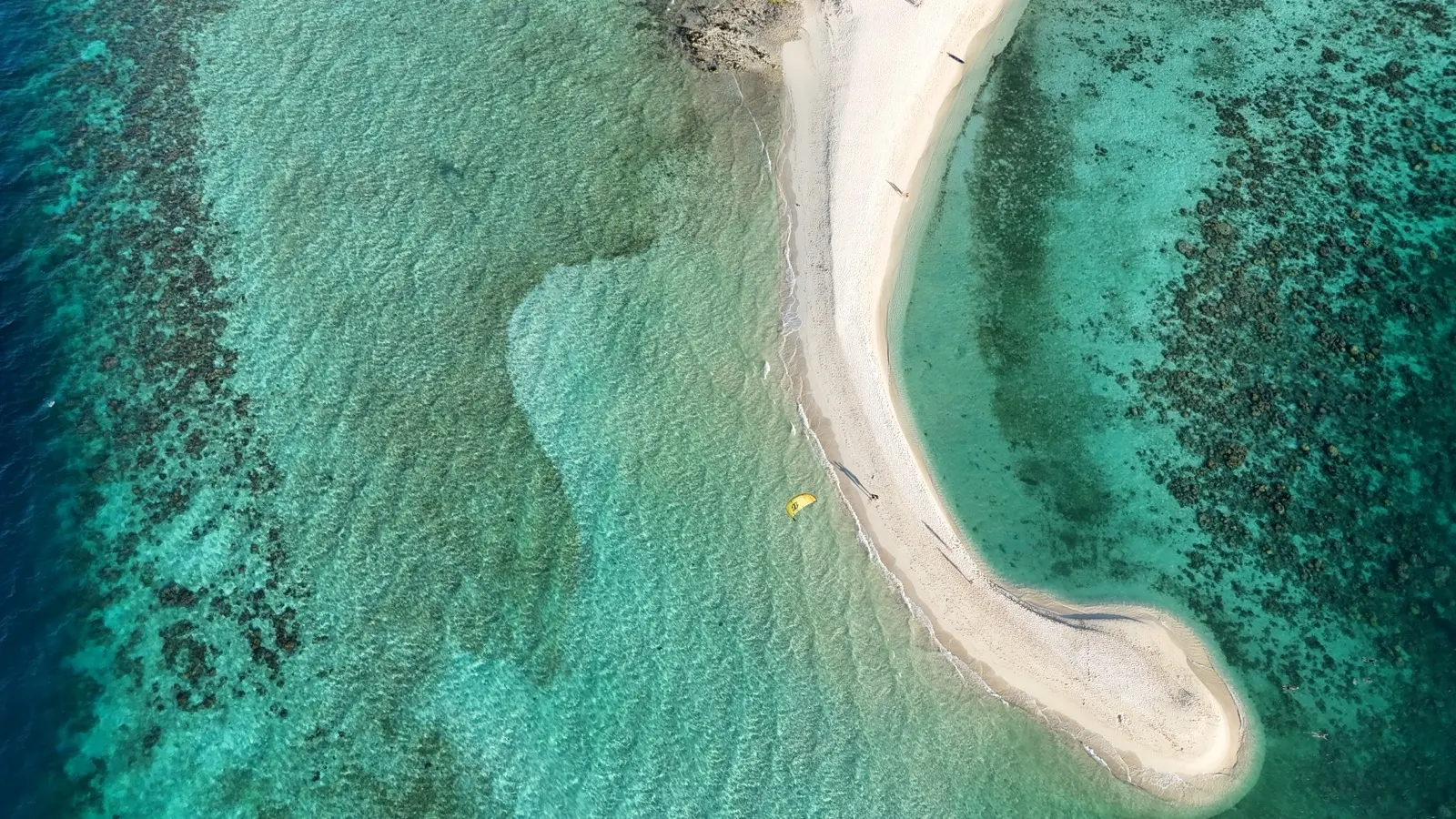 Kite and beachgoers on curving sandbar, aerial view