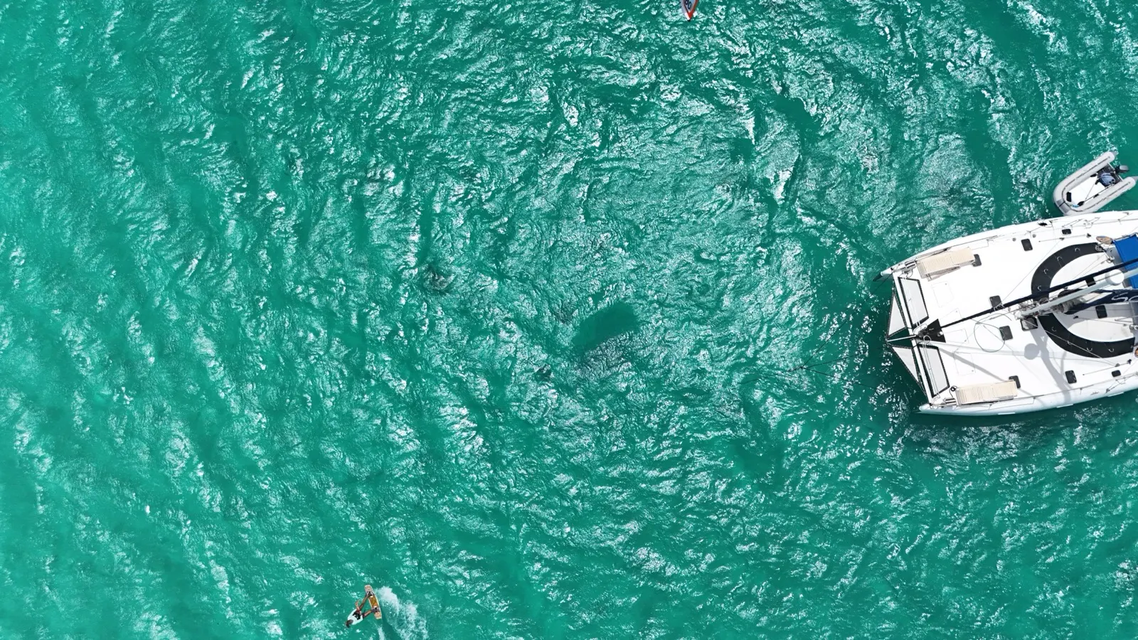 Aerial of kitesurfer near anchored catamaran
