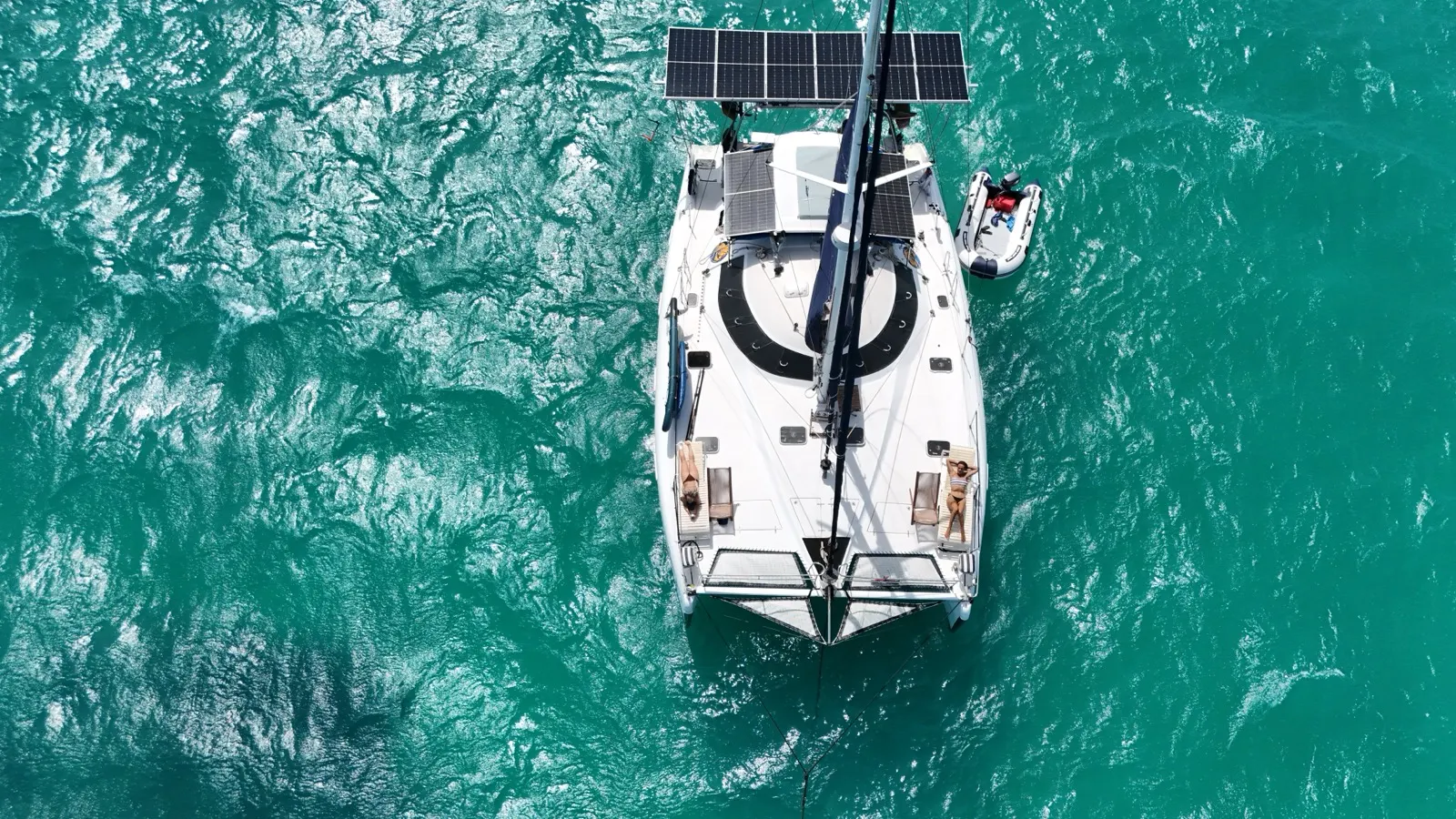Aerial drone-selfie of catamaran, sunbathers on deck