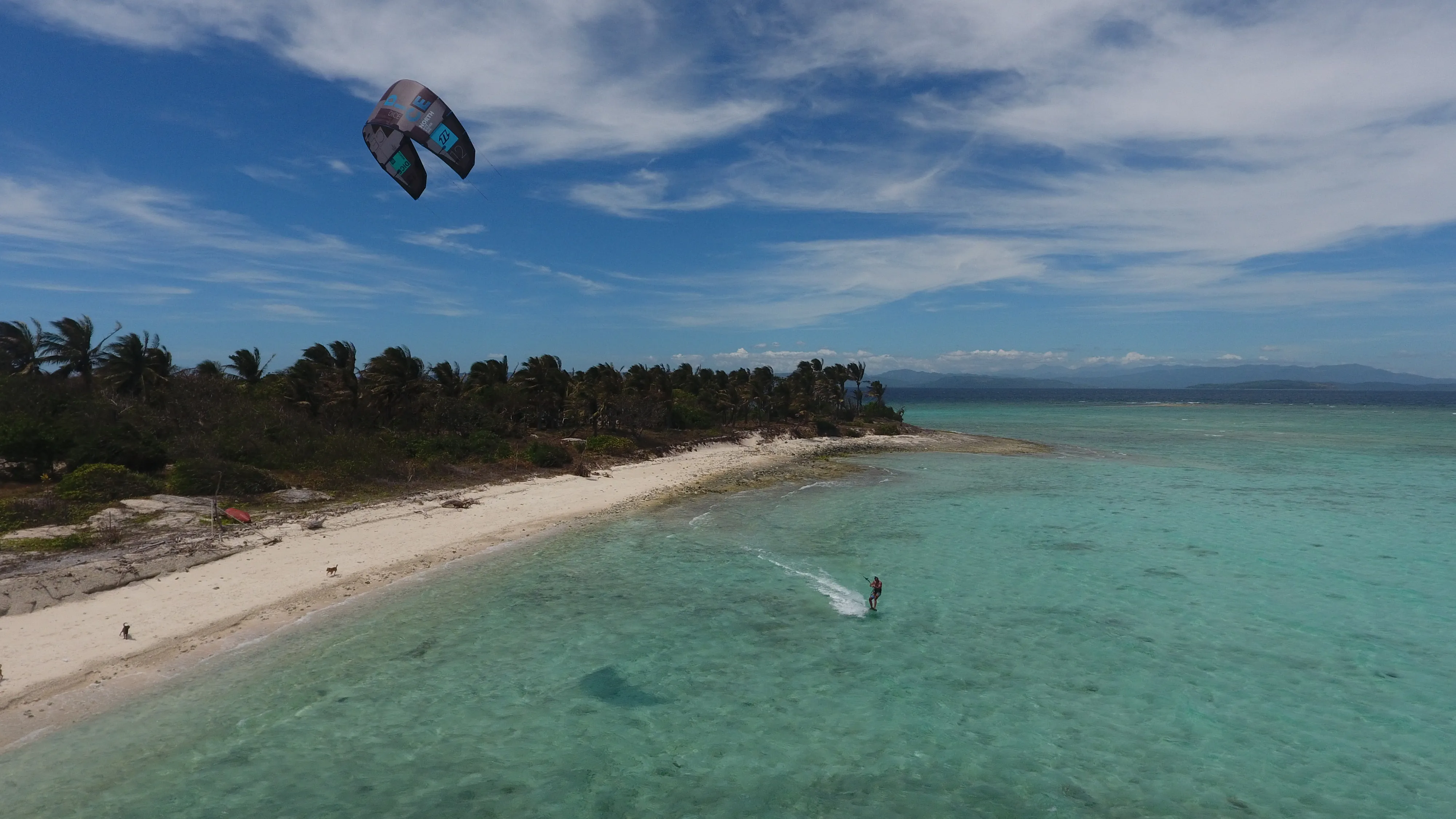 Kitesurfer near a rocky cliff with Soniya anchored in the background off Mindoro