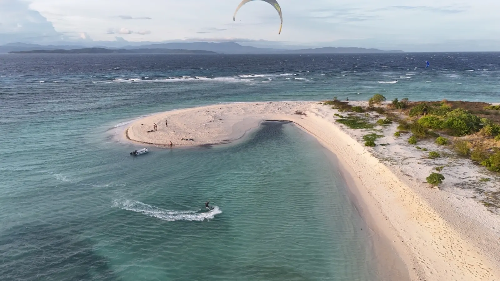 Kitesurfer jumping high near a sandbar with kite overhead