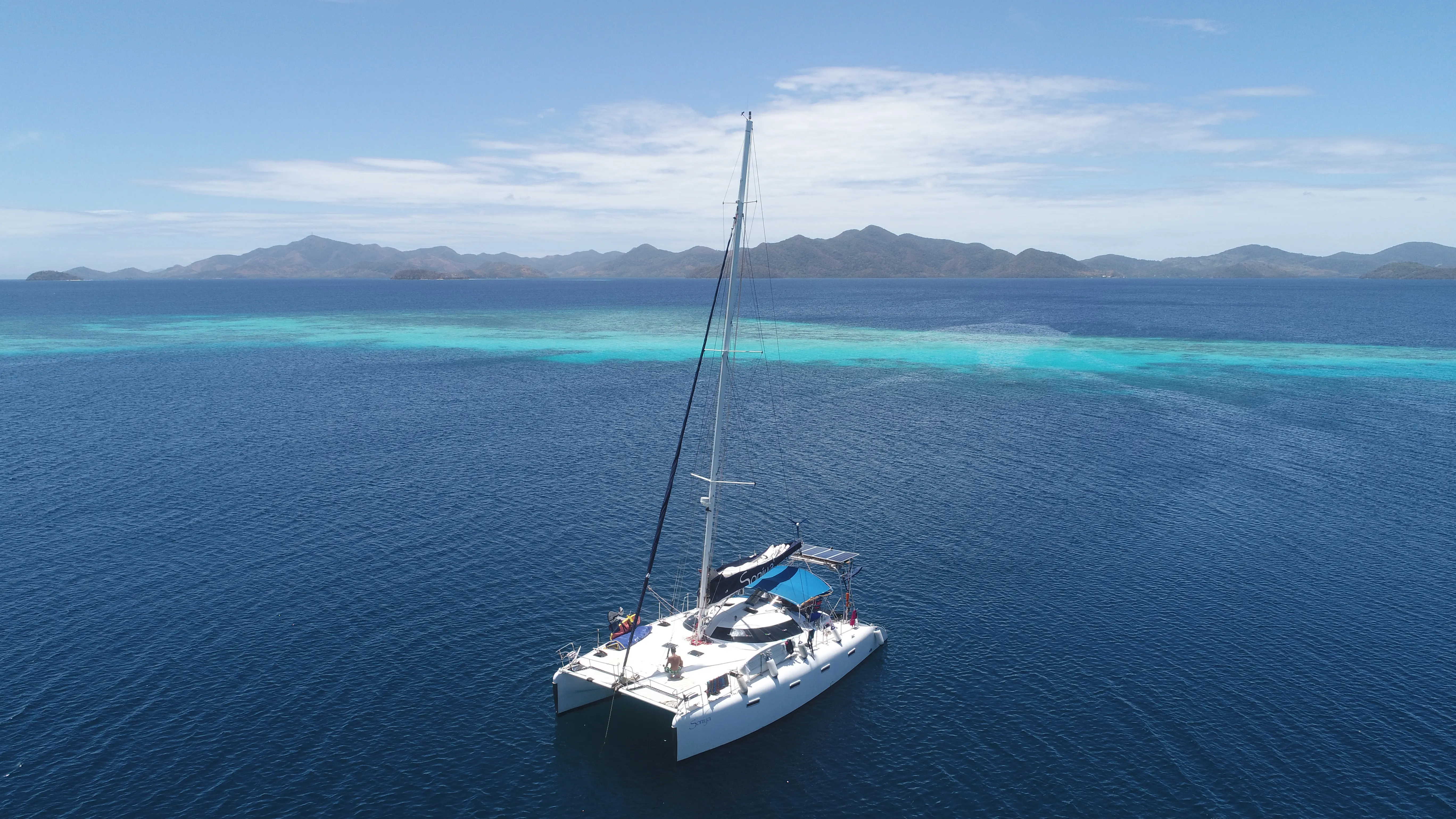 Four kiteboarders riding together across turquoise water