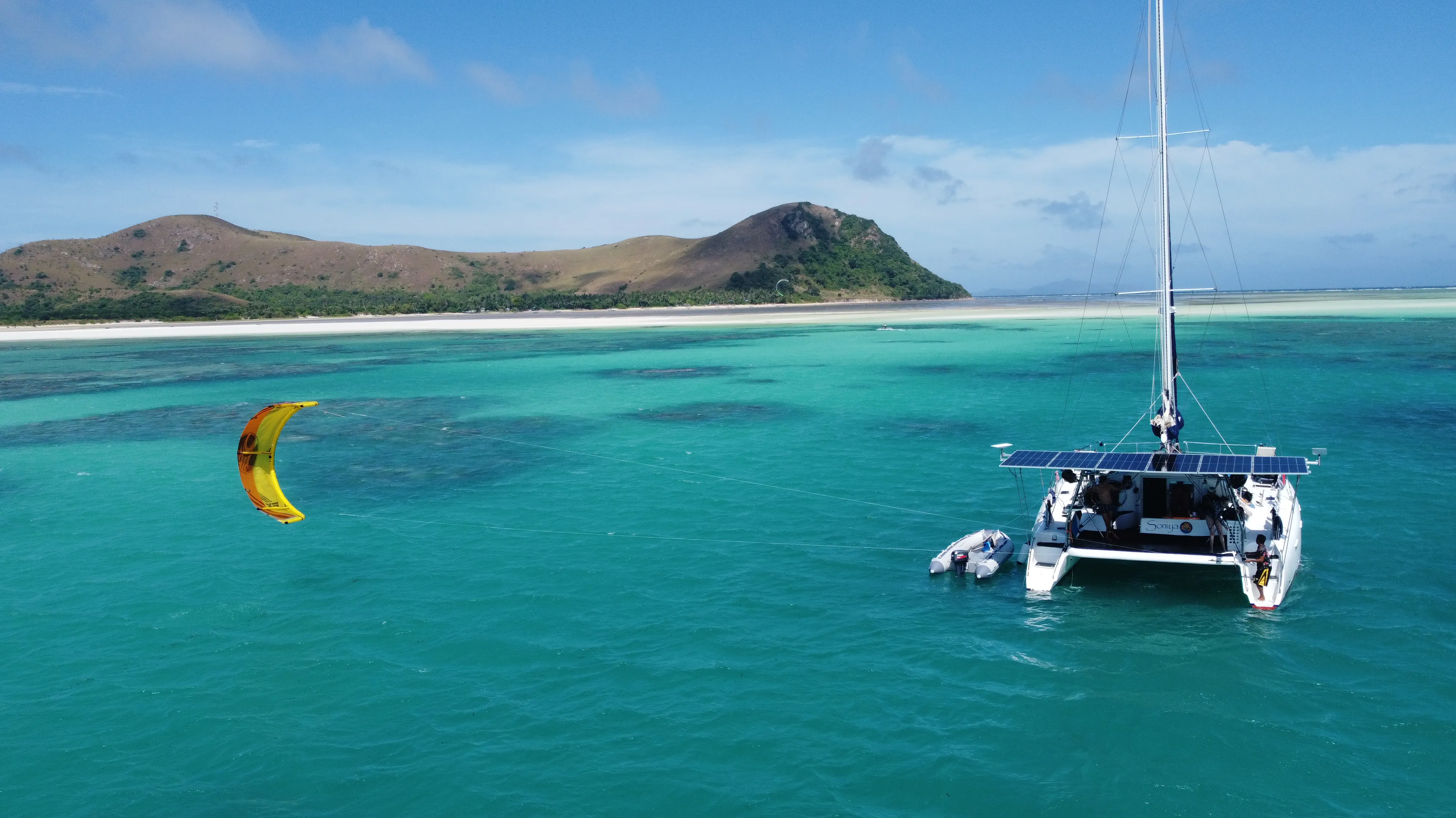 Aerial view of Soniya under sail with a kite flying nearby off Palawan