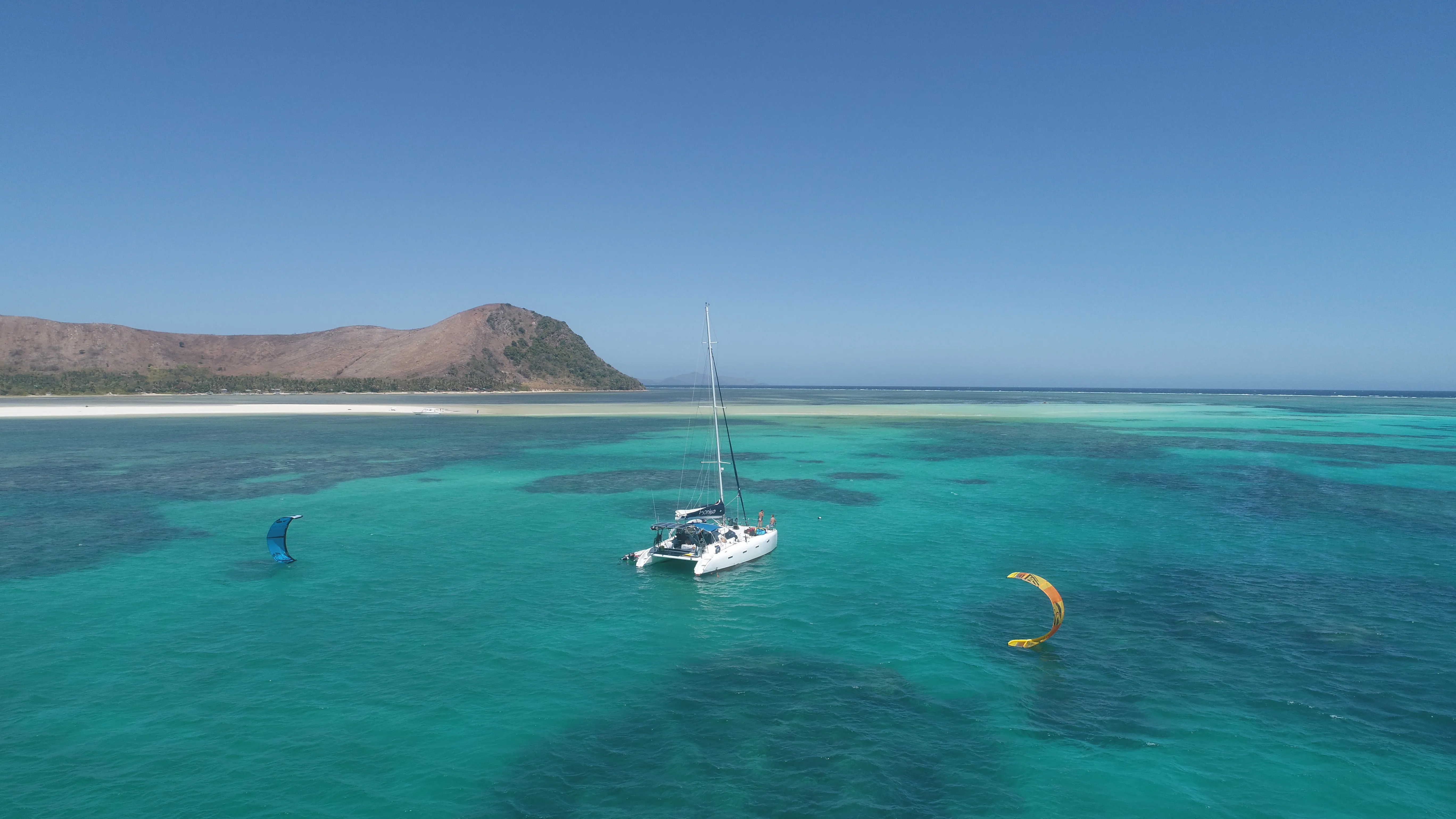 Aerial view of Soniya anchored beside a kitesurfer over a Palawan reef