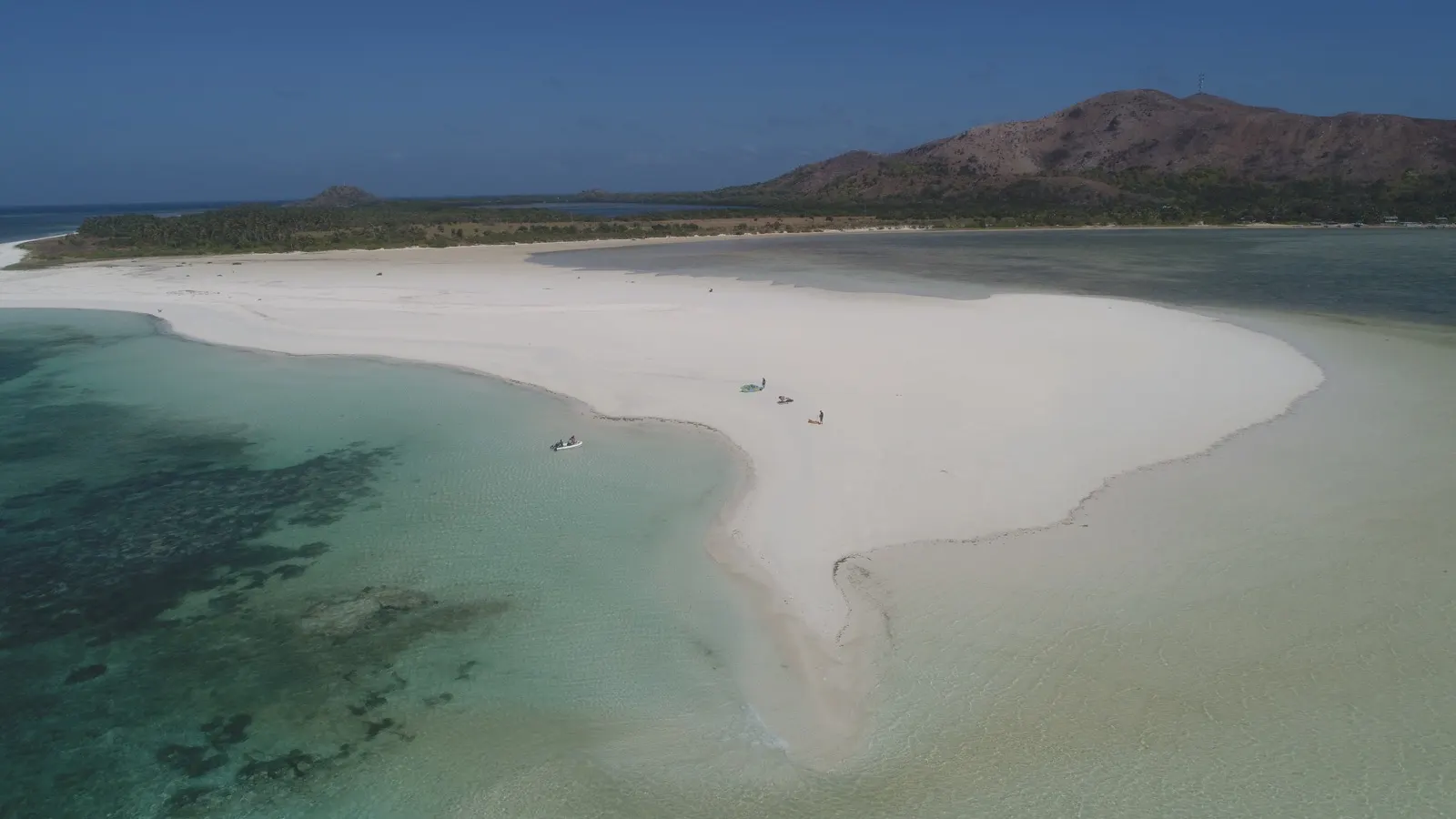 Sandbar with dinghy, people and kite gear at water's edge
