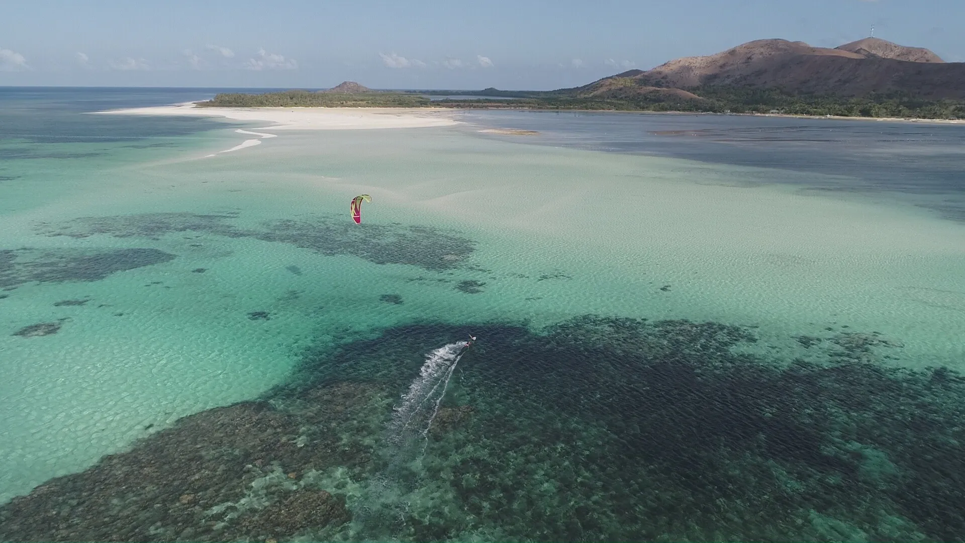 Aerial view of a kitesurfer on a Palawan sandbar in golden evening light