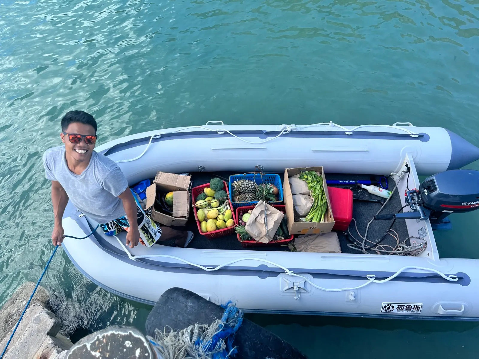 Smiling crew member on dinghy loaded with fresh produce