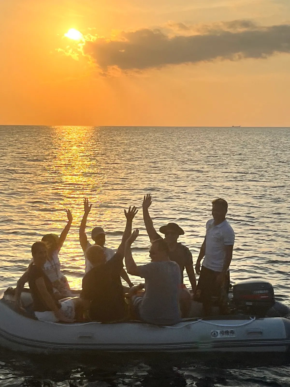 Group cheering from dinghy at sunset