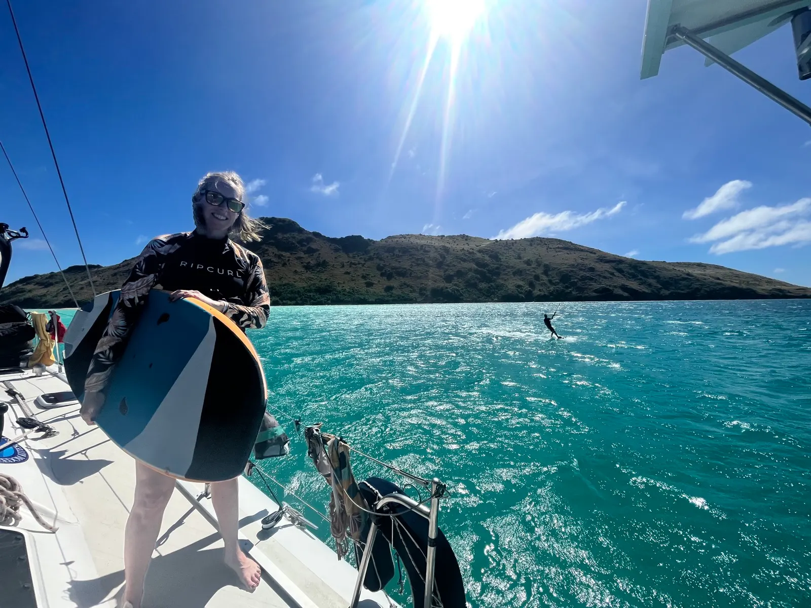Woman holding kiteboard on sunny boat deck
