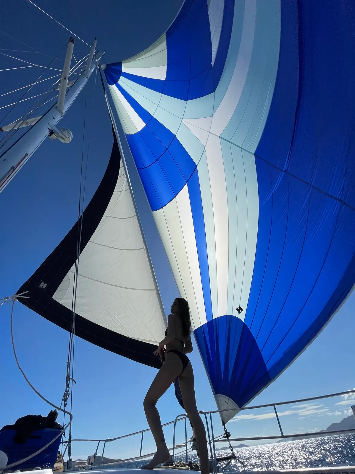 Crew member climbing rigging beneath billowing sails